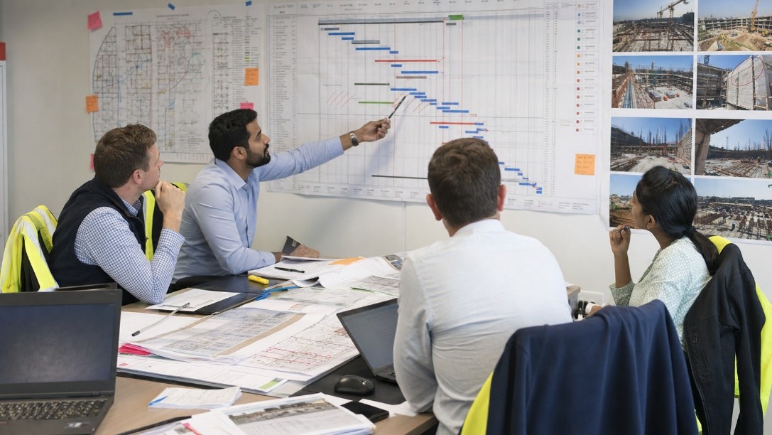 Team reviewing a project schedule and Gantt chart on the wall